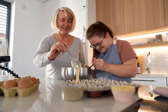 care worker and lady with downs syndrome making cakes